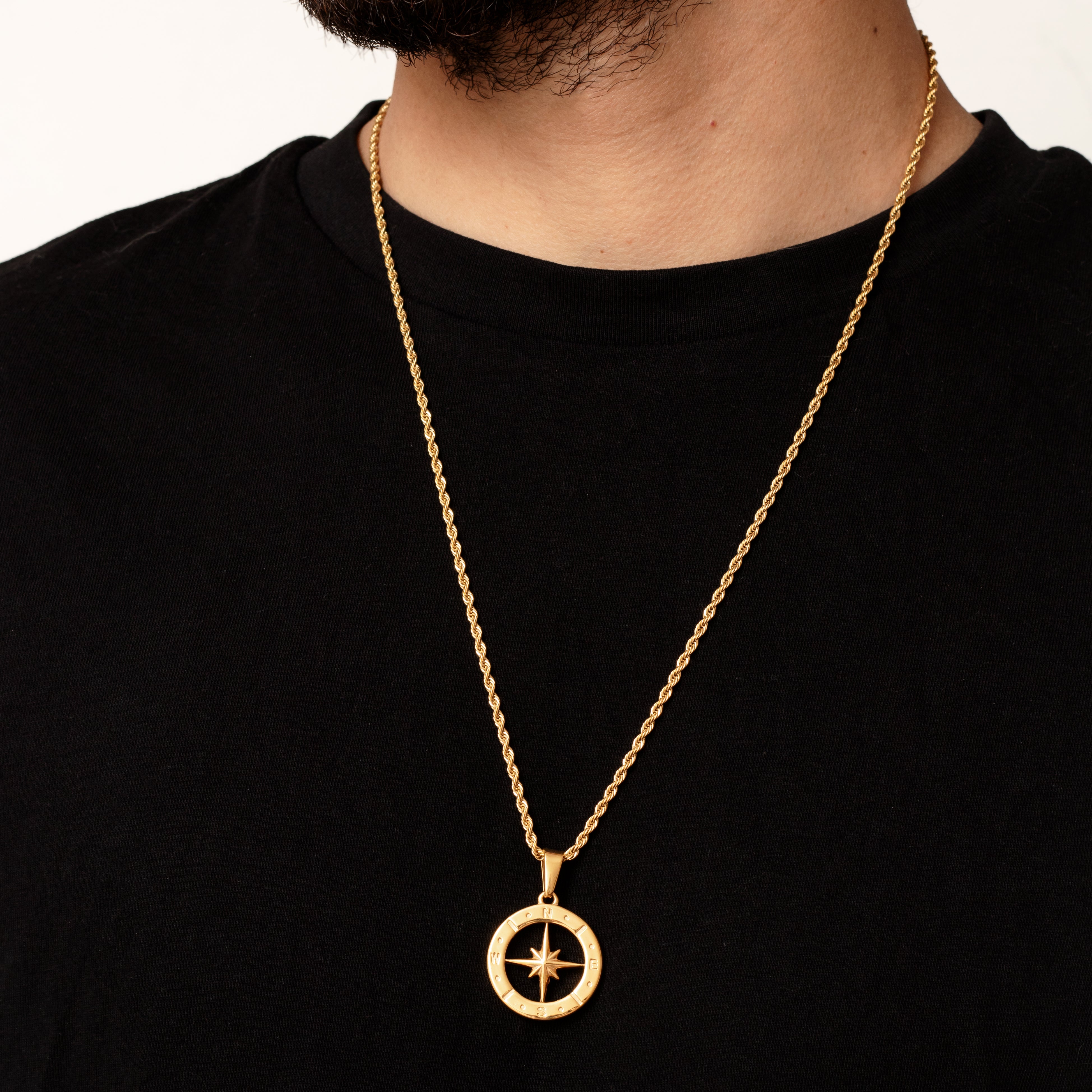Gold necklace with a north star compass pendant on a black shirt
