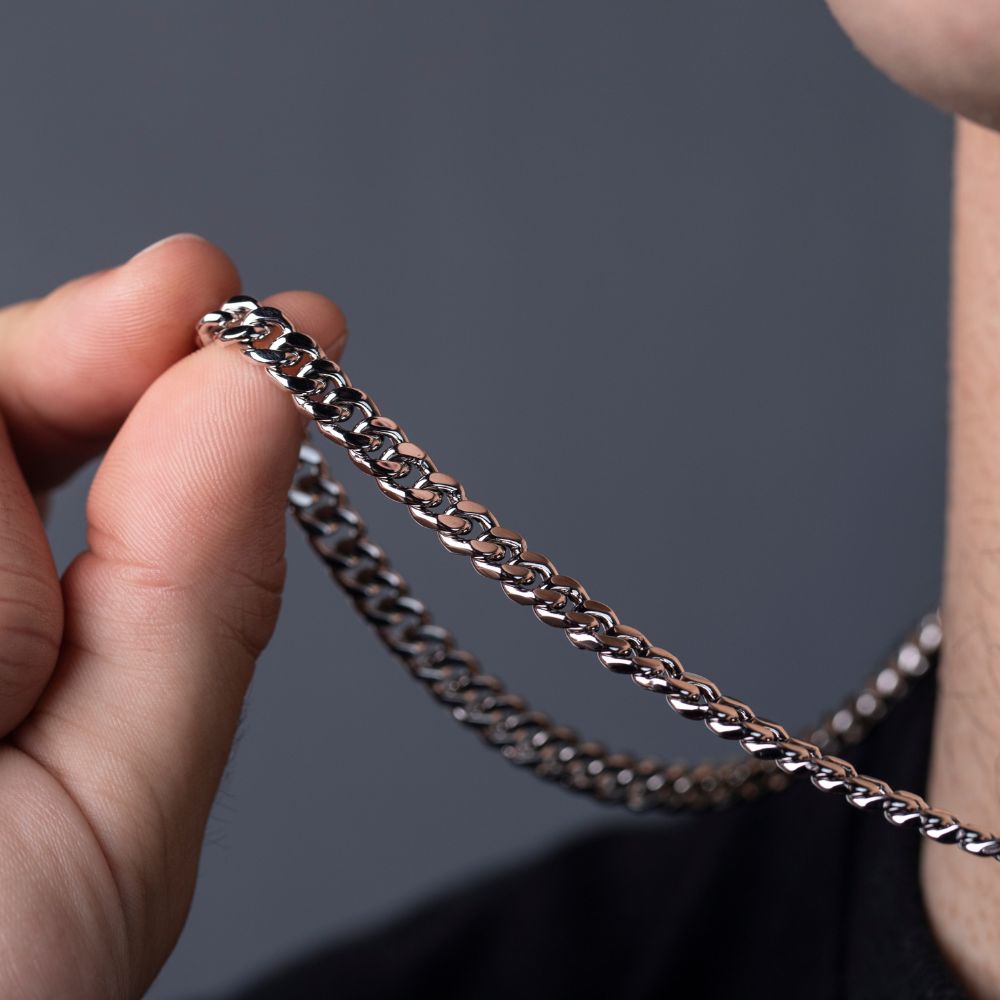Hand holding sterling silver Cuban link chain, close-up of curb link texture