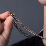 Hand holding sterling silver Cuban link chain, close-up of curb link texture