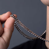 Hand holding sterling silver Cuban link chain, close-up of curb link texture