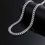 925 silver Cuban link chain draped over display stand, close-up on black background