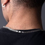 Back view of silver Cuban chain clasp on man's neck, earrings visible