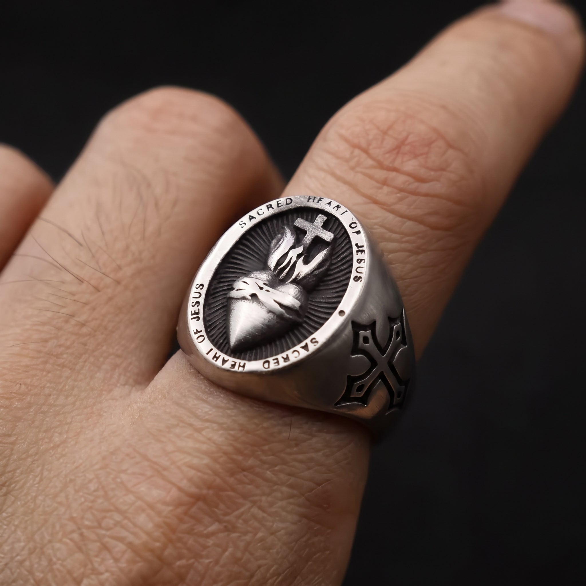 Man wearing the Sacred Heart of Jesus stainless steel signet ring on his finger, with cross engraving on the side