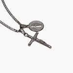 Silver necklace with a cross and round pendant on a white background